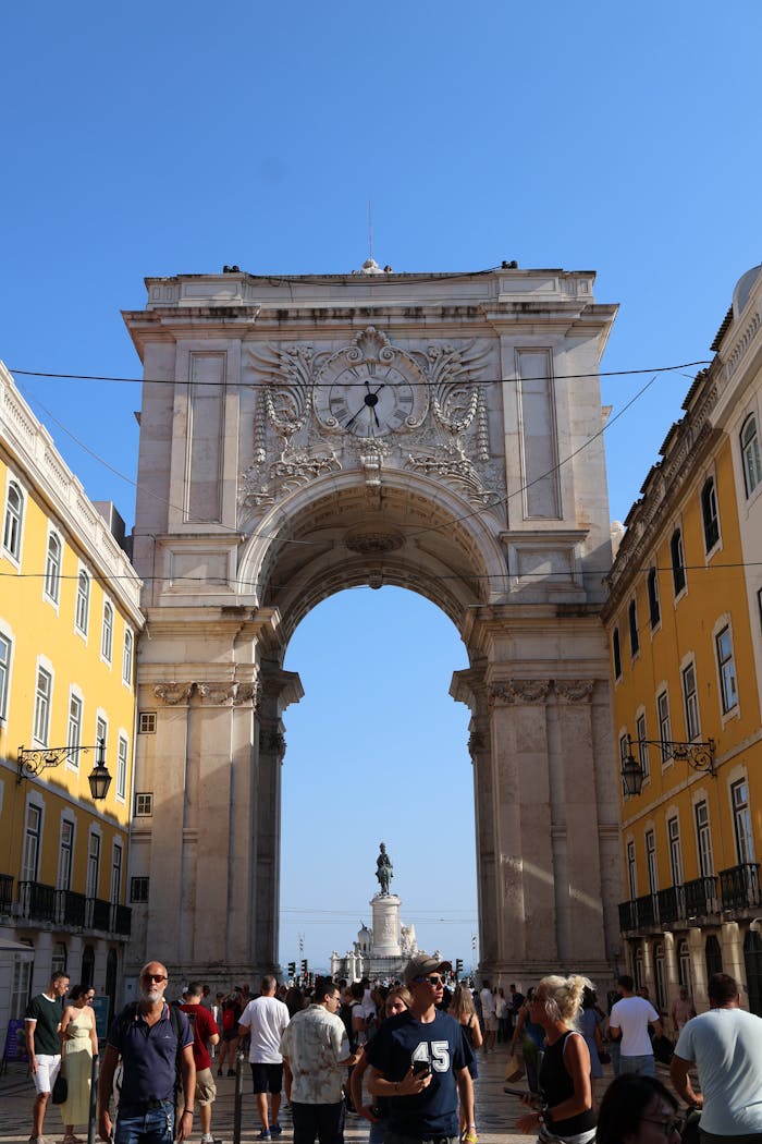 about-01 View of the iconic Rua Augusta Arch in Lisbon under a bright day with blue sky.